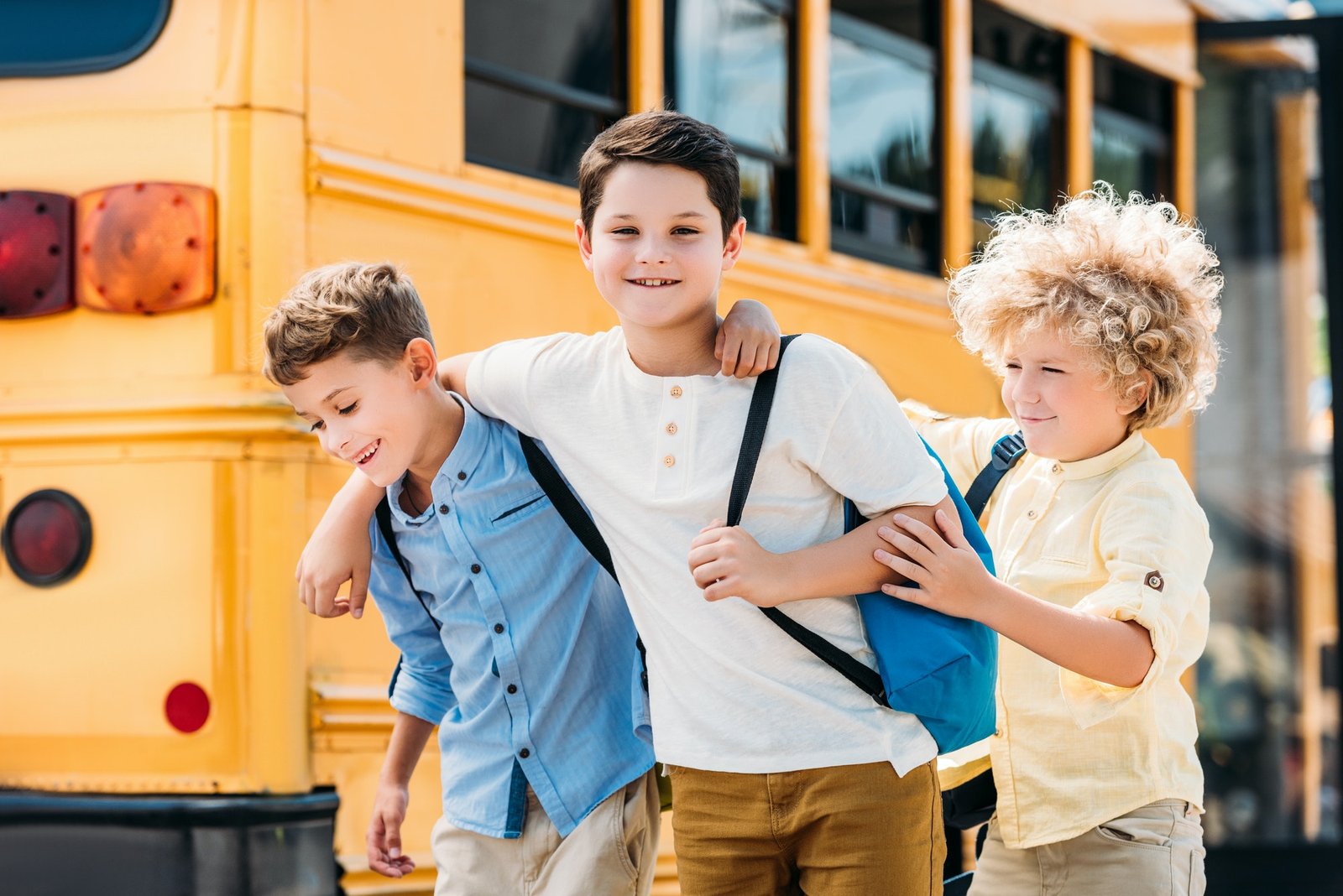 adorable little schoolboys having fun together in front of school bus